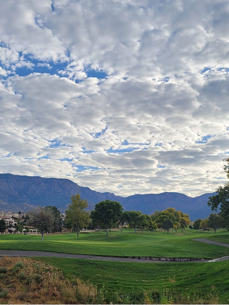 Wide fairway under clouded skies with the Sandia Mountains behind at Tanoan Country Club in Albuquerque, New Mexico
